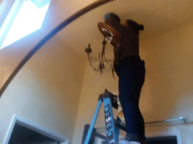Electrician installing a chandelier in a Topanga residence